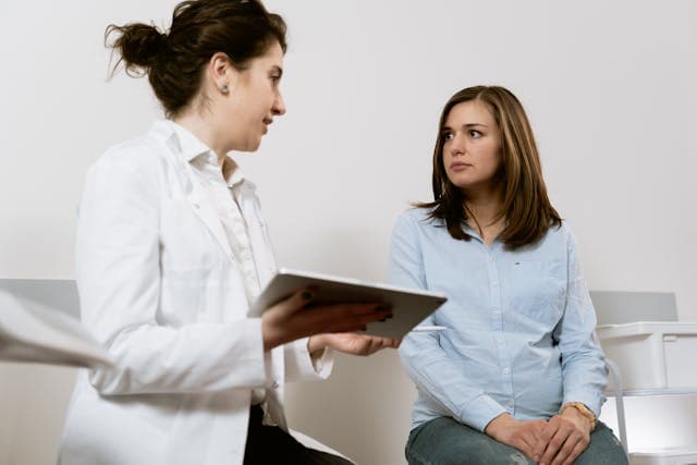 Public health professional discussing care options with a woman during an individual consultation, illustrating patient-centered and rights-based health services.